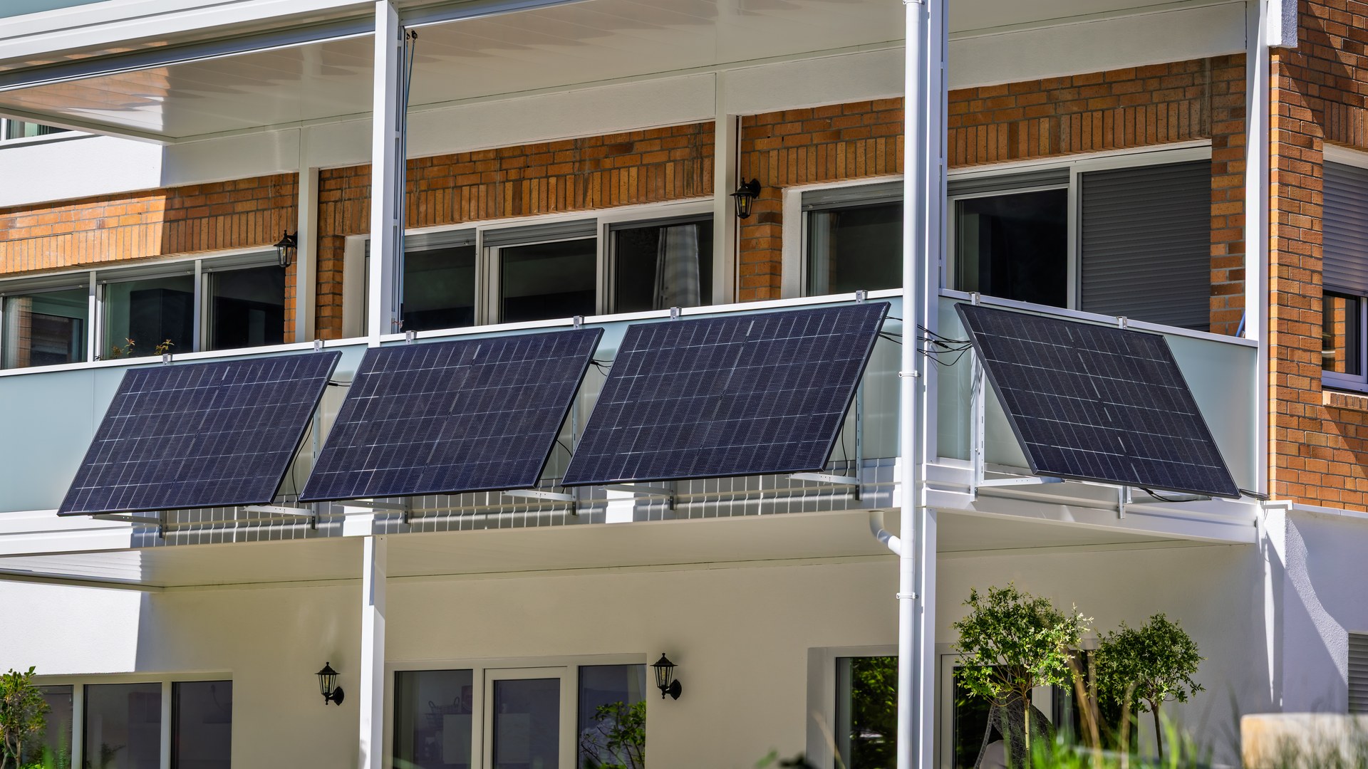 Vier Solarmodule als Balkonkraftwerk an Mehrfamilienhaus-Balkon montiert