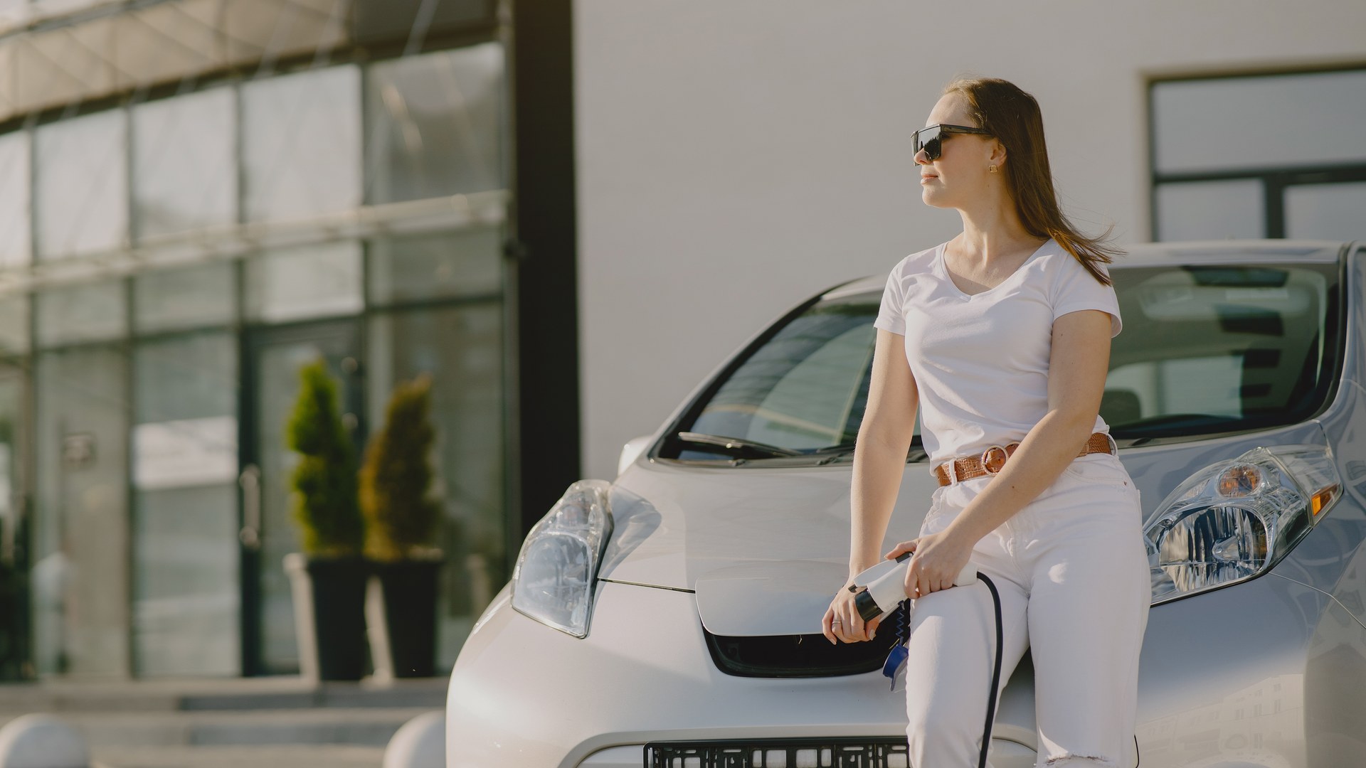 Frau lehnt an günstigem Elektroauto beim Laden – Einstieg E-Mobilität
