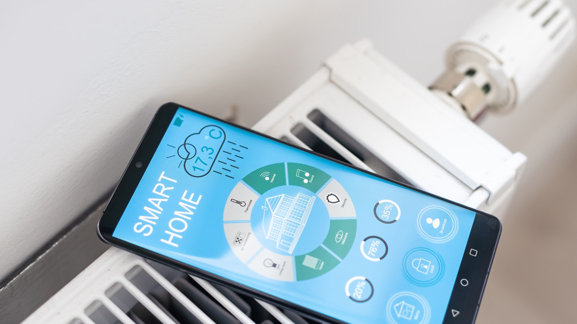 Smartphone mit Smart-Home-App liegt auf Heizkörper – smarte Thermostate im Vergleich